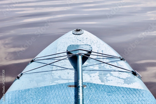 Fototapeta Paddleboard and surf board with paddle on blue water surface close up. Surfing and SUP boarding equipment in sunset lights close-up. Outdoor water sports. Surfing lifestyle backgrounds. Drifting surf
