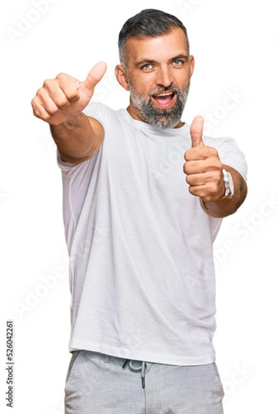 Fototapeta Middle age handsome man wearing casual white tshirt approving doing positive gesture with hand, thumbs up smiling and happy for success. winner gesture.