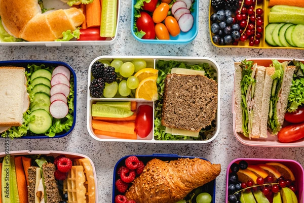 Fototapeta Shot of school lunchboxes with various healthy nutritious meals on stone background