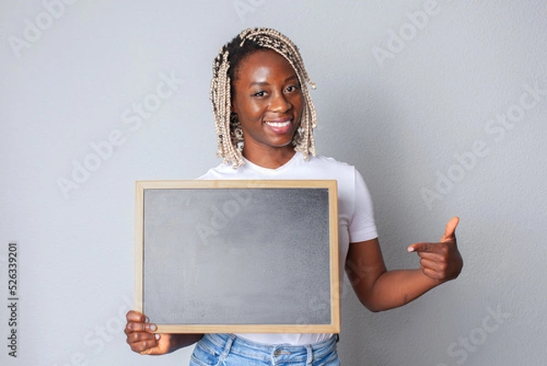 Obraz Mujer negra soniendo señalando una pizarra que sujeta en la mano. Anuncios para comercios 