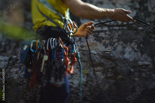 Fototapeta Climber works with a rope during the ascent,  face is not visible, close-up.