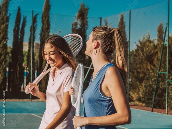 Fototapeta Amigas felices jugando al tenis al aire libre durante el verano