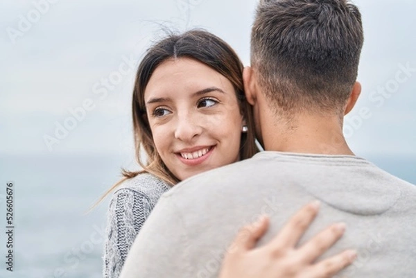 Fototapeta Man and woman couple smiling confident hugging each other at seaside