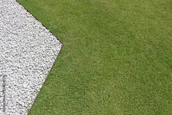 Fototapeta Blank background from above view of the contrast between an angled straight edge of white stone gravel and green garden lawn