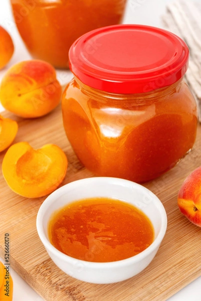 Obraz Homemade fruit preserve and fresh whole apricots on cutting board. Apricot jelly in glass jar.