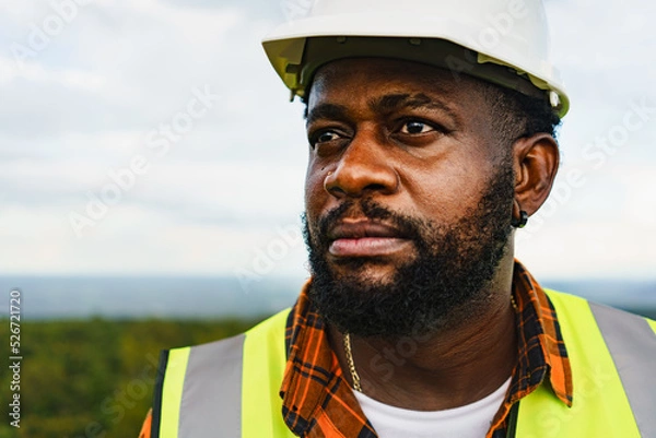 Fototapeta Close up portrait of black engineer man with serious face expression while working outdoor.