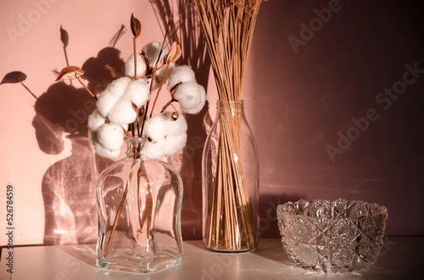 Fototapeta Abstract nature scene with composition of glass and dry branches of cotton. Neutral beige background for cosmetic, beauty product branding, identity and packaging.