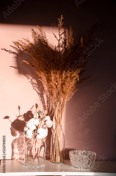 Fototapeta Abstract nature scene with composition of glass and dry branches of cotton. Neutral beige background for cosmetic, beauty product branding, identity and packaging.
