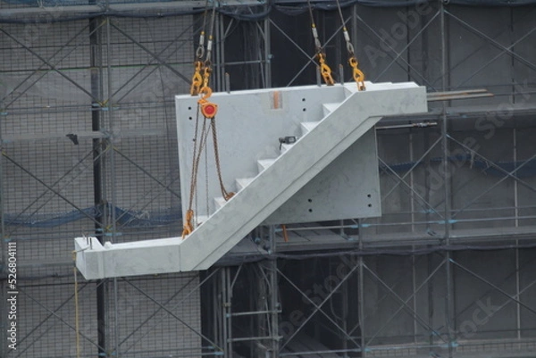 Fototapeta ビル建設現場で大型クレーンによる階段ユニット吊り上げ作業