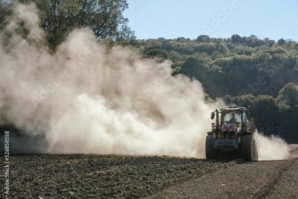 Obraz un tracteur qui laboure avec un muage de poussière