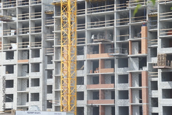 Fototapeta Full-color horizontal photo. Urban landscape. Part of the facade of a building under construction. Geometric linear composition with windows.