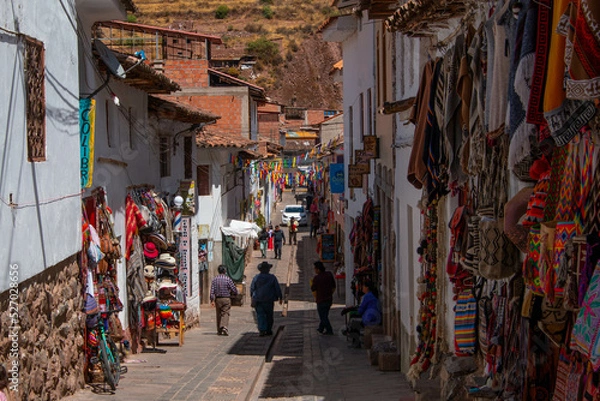 Fototapeta Typical street in the town of Pisac with its colorful stores, mountain view and a beautiful blue sky with clouds, in Peru.