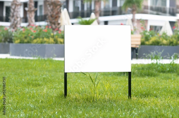 Fototapeta Empty sign, advertising mock-up, banner on grass near pavement in city green park.Copy space for text.Information board on white background. 