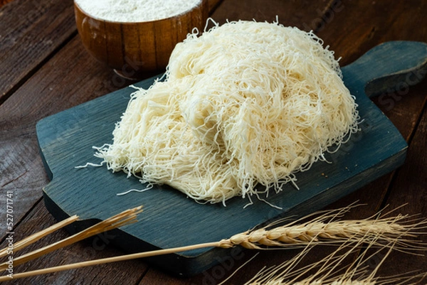 Obraz Kataifi dough on a wooden board and on a wooden table.