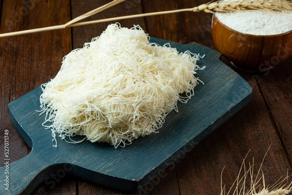 Obraz Kataifi dough on a wooden board, not cooked dough, wooden table.
