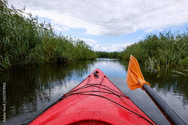 Fototapeta Kayaker point of view. Kayak bow with a view on the river and rushes.   River kayaking concept. Active vacations in wild nature.