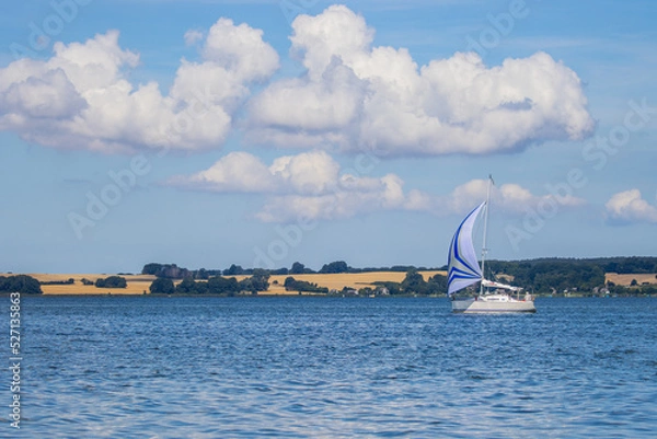 Fototapeta Landscape with the sea and a sailing boat against the backdrop of the island of Rügen in Germany