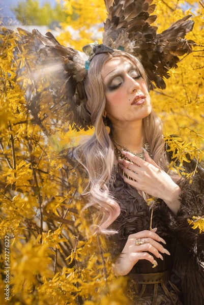 Obraz Fairy girl in a crown of feathers and long blond hair posing in yellow flowers