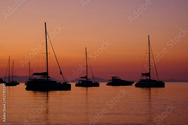 Fototapeta Several yachts standing in the bay against the sky during sunrise.
