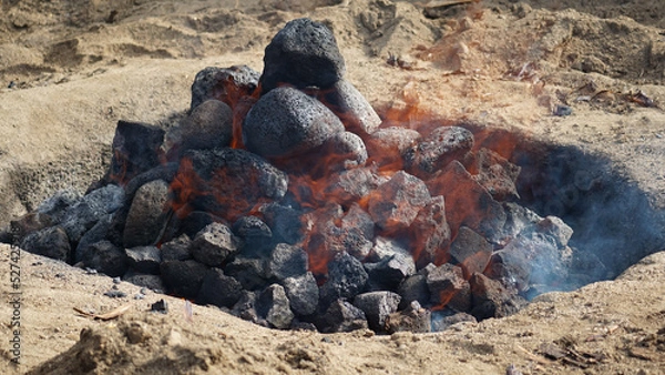 Obraz Hot coals and rocks smoldering as the imu is prepared for a luau in Hawaii.