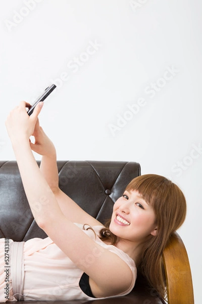 Fototapeta 部屋でスマホを使う女性