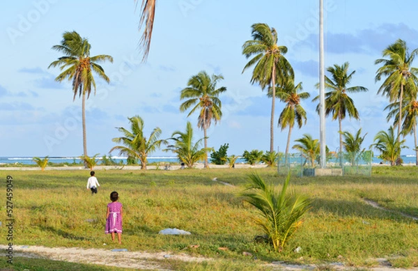 Fototapeta Kids playing under palm trees on Maldive islands