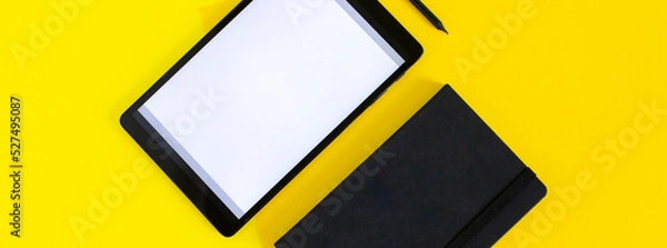 Fototapeta Home office flat lay with tablet and black notebook on yellow background