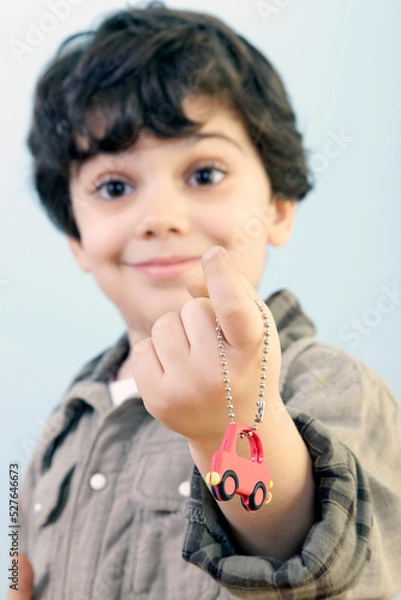 Fototapeta Boy is Showing Us a Car Key Against Blue Background