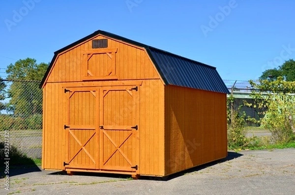 Fototapeta American style wooded shed. A shed is typically simple, single-story roofed structure in a back garden or on an allotment that is used for storage, hobbies, or as a workshop. Exterior view
