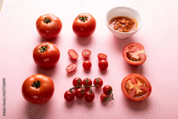 Fototapeta High angle view of fresh various tomatoes with puree in bowl on pink background