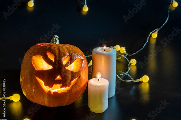 Obraz Halloween carved pumpkin. The smiling face of Jack O Lantern. Illuminated by a burning candle inside the scary Jack Lantern. Pumpkin decoration. Happy Halloween. yellow lanterns on black background