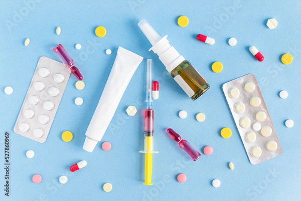 Fototapeta Top view of chaotically arranged medicines on a blue background