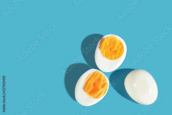 Obraz Boiled eggs slice with shadow on blue background with sunlight. Copy space concept and torether idea
