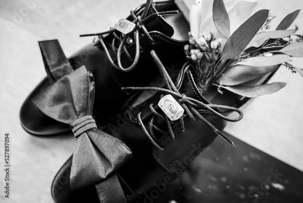 Fototapeta Black and white image of groom's shoes with bowtie and cuff links resting on top