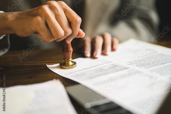 Fototapeta close-up of person stamping documents to approve agreements,