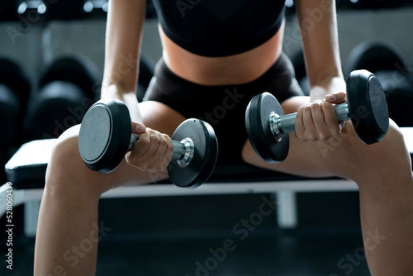Fototapeta Beautiful Caucasian woman wearing workout clothes Use your arms to lift small dumbbells in the gym. Fat Burning Motivation to have a good body shape. concept sustainable life