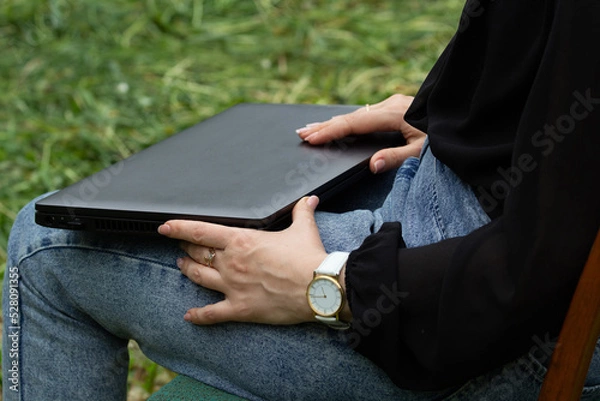 Obraz female hands open a laptop, on the street, in the fresh air, the beginning of the working day, free schedule,