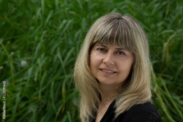 Obraz close-up portrait of a woman, kind, sweet, beautiful, confident, smiling, against the background of green grass