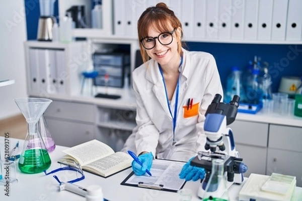 Fototapeta Young woman scientist write on document at laboratory
