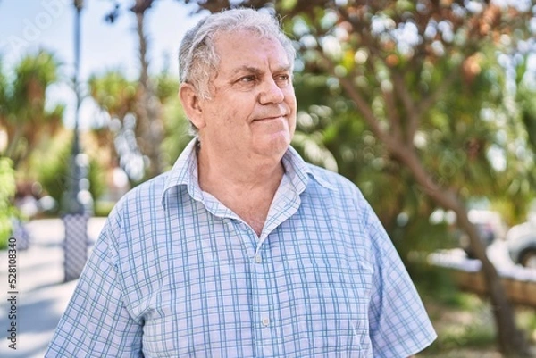 Fototapeta Middle age grey-haired man smiling confident walking at park