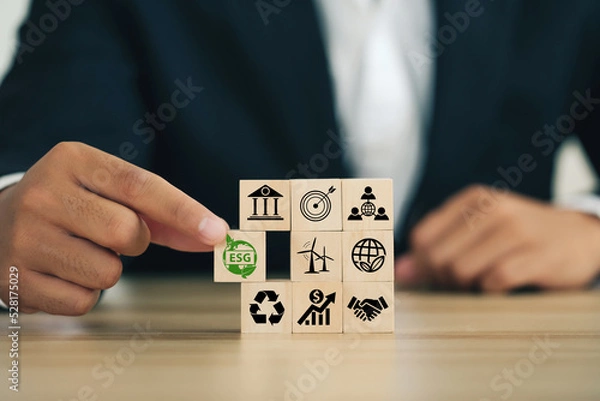 Fototapeta ESG concept of environmental, social, and governance. Sustainable corporation development.Businessman Hand holding Wooden blocks with ESG icons standing with other ESG icons.Net Zero.