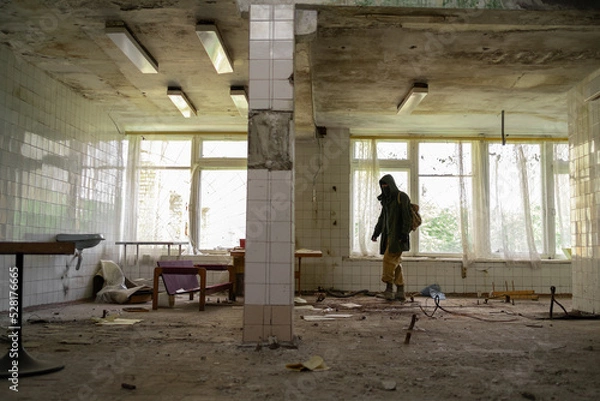 Fototapeta Nuclear post-apocalypse survivor in abandoned building, stalker life after war, man traveling on foot in a post-apocalyptic world.