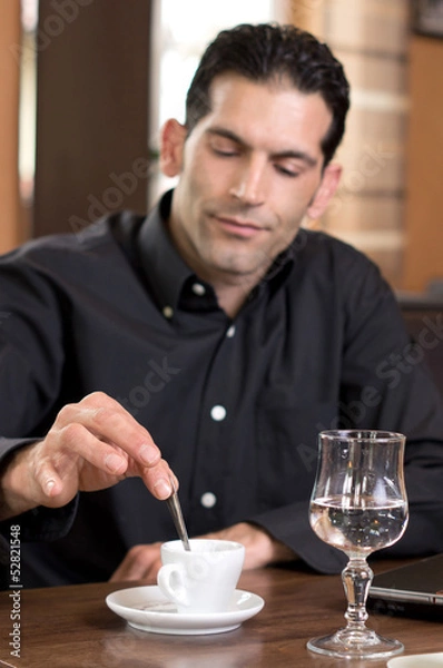 Fototapeta Mann beim umrühren eines Espresso