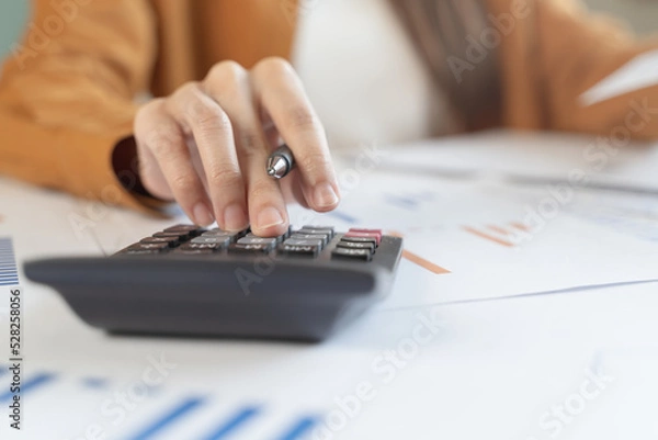 Fototapeta person using calculator calculating tax refund on the table