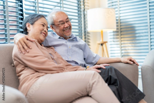 Obraz Senior couple sitting on the sofa at home watching television and relaxation together. Enjoyment to spend time together with smile and happy. Modern elderly lifestyle and retirement concept