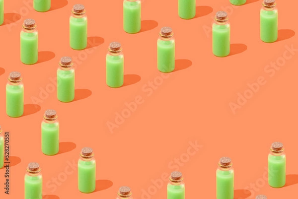 Fototapeta Minimal Halloween concept with neon green magic potion bottle pattern on orange background with copy space. Creepy, spooky holiday aesthetic.