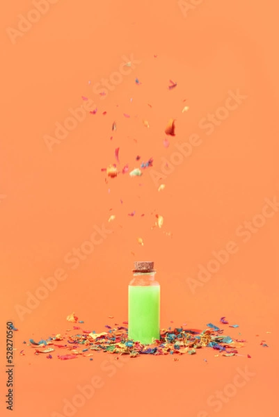 Fototapeta Minimal Halloween concept with a neon green magic potion bottle and colorful confetti on orange background. Creepy, spooky holiday aesthetic. Party idea.