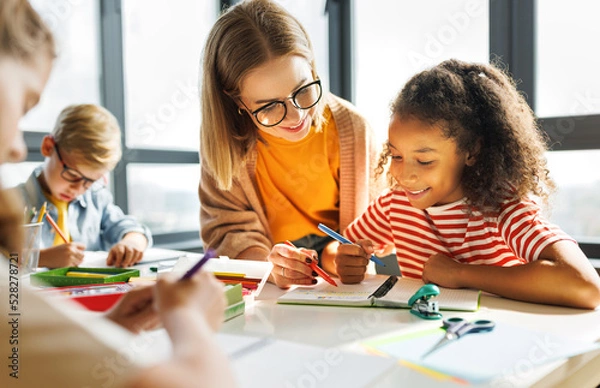 Obraz Teacher helping children with schoolwork
