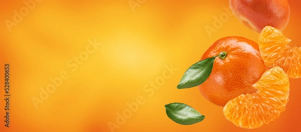 Fototapeta mandarines with slices and leaves flying on orange background