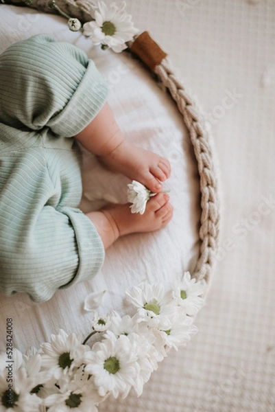 Obraz cute baby feet, white flowers and wicker cradle